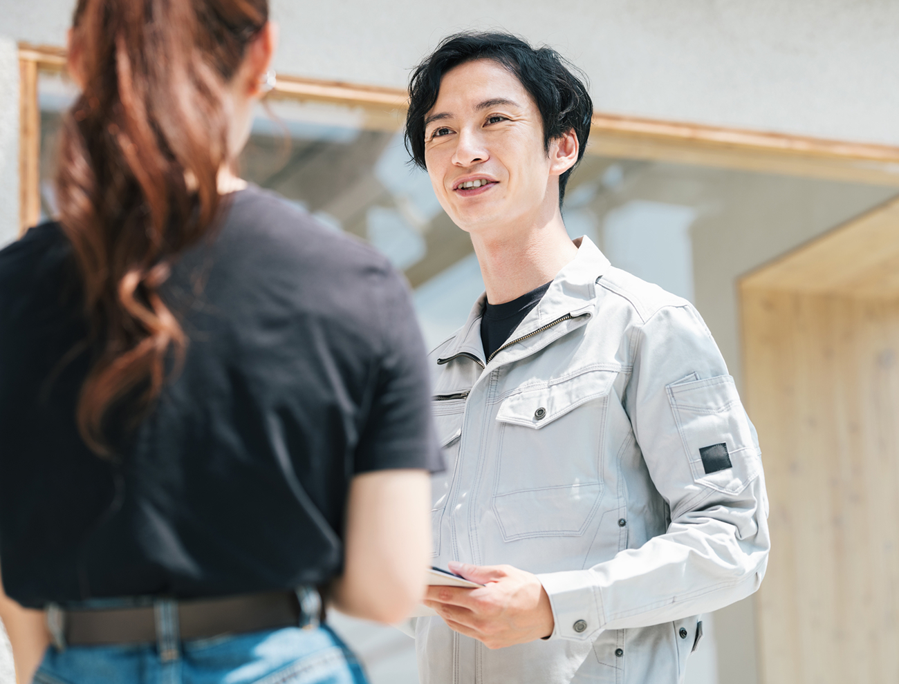 作業着を着て話す男性と女性の後ろ姿